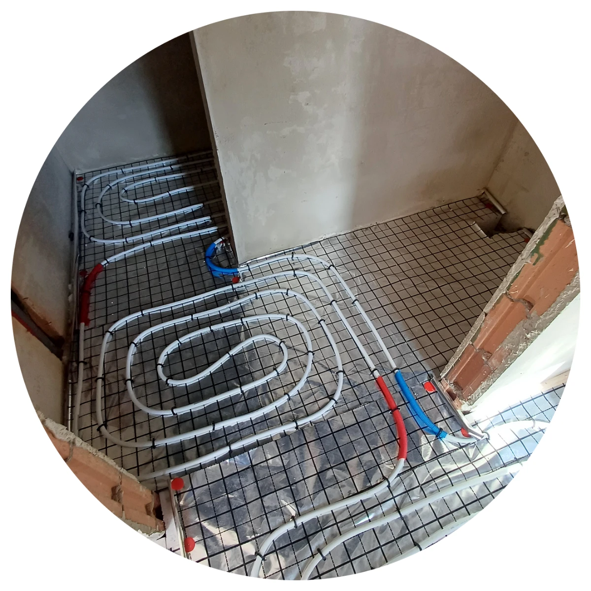 Rozłożona instalacja ogrzewania podłogowego z białymi rurami na ruszcie z siatki pod wylewkę